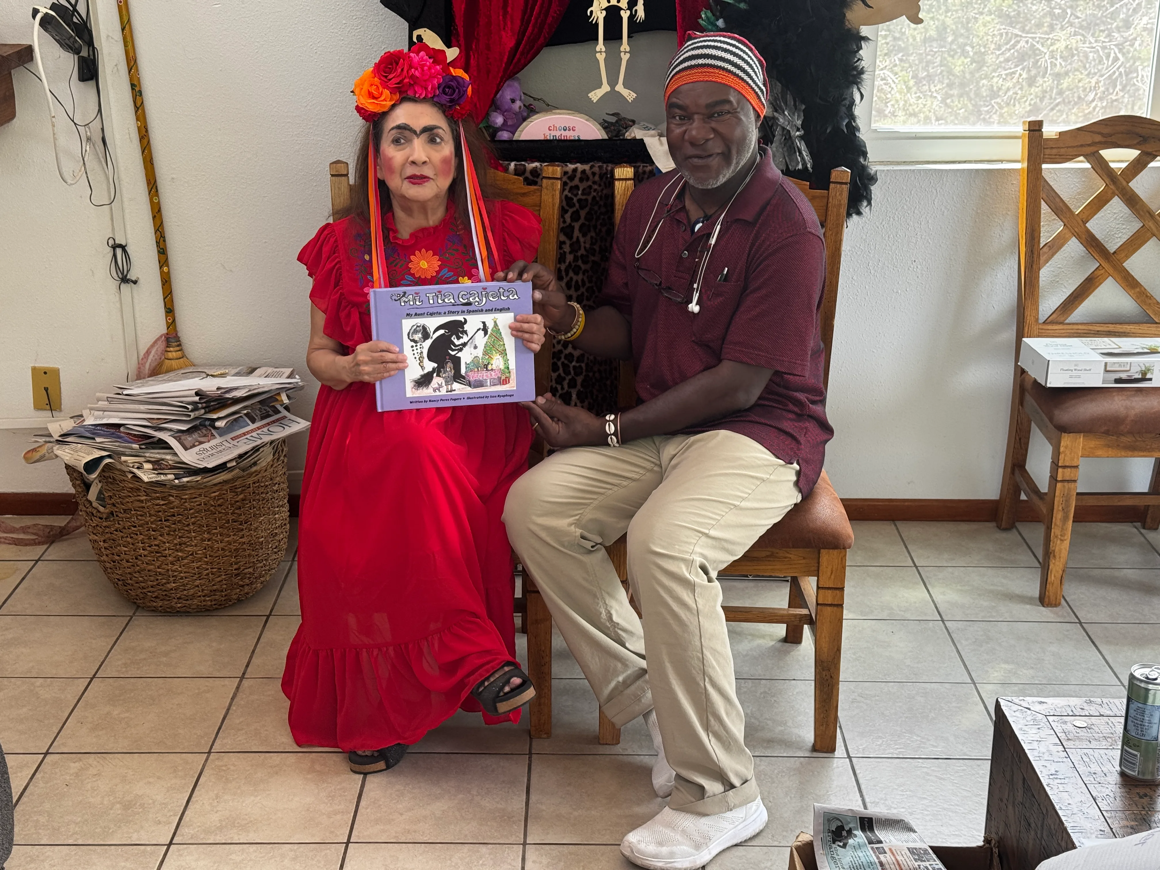Nancy Perez Fugere and Issa Nyaphaga sitting together with the book